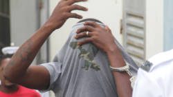 Zeno Audain uses his shirt to hide his face outside the Serious Offenses Court on Monday. (iWN photo)
