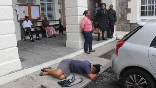 Persons look on the woman lying on the ground outside the High Court on Thursday. (iWN photo)