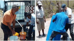 Opposition Leader Godwin Friday, left, and Deputy Director of Grenadines Affairs, Herman Belmar, right, join CWSA employees in the water distribution exercise. 
