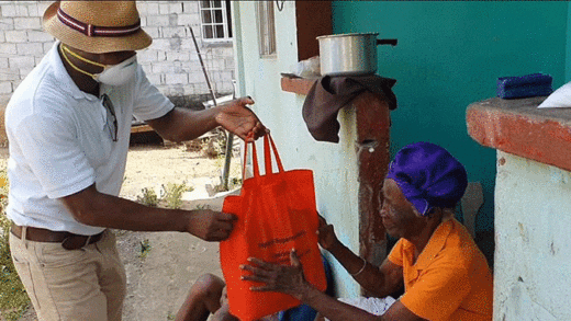 Speaker of the House of Assembly and ULP candidate for North Leeward, Carlos James hands over one of the packages to a resident.
