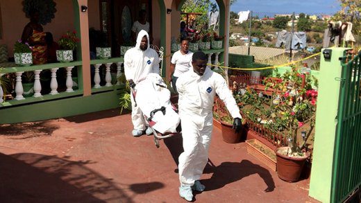 A detective keeps a close eye as funeral home workers remove the body of Moralis Delano Stanley from the house in Chauncey on Tuesday. (iWN photo)