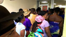 Persons crowd while awaiting services outside a Kingstown business place on Friday. (iWN photo)