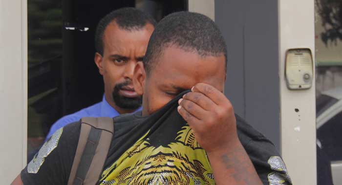 The accused, Jason Delplesche hides his face as he leaves the Kingstown Magistrate's Court on Monday. (iWN photo)