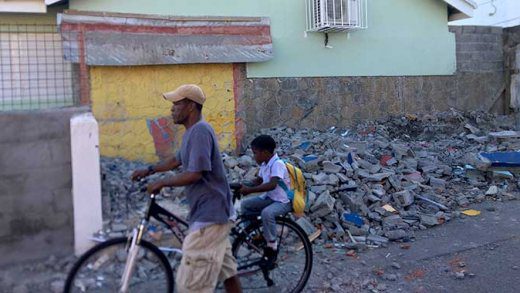 An unidentified man and a student pass in front the rubble of the demolished shop at the Kingstown Government School in Stony Ground last week. (iWN photo) 