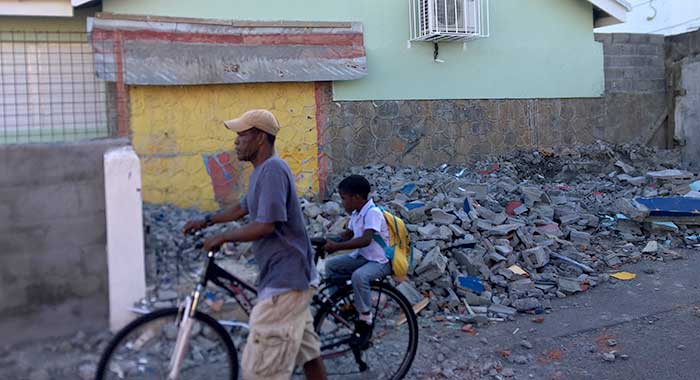 An unidentified man and a student pass in front the rubble of the demolished shop at the Kingstown Government School in Stony Ground last week. (iWN photo) 