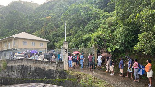 Voters ques up in light rain ahead of the 7 a.m. opening of polls in Rillan Hill, South Leeward, Thursday morning. (iWN photo)