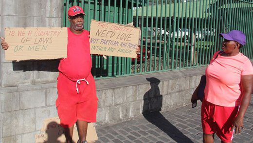 A passer-by reads Joel Poyer's placards outside Parliament on Monday. (iWN photo)