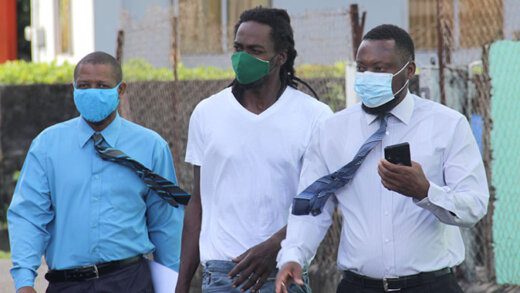 The accused, Fitzgerald Phillips, centre, escorted to court by detective Corporals Hoyte, left, and David on Jan. 26, 2021 (iWN photo)