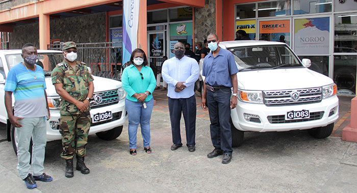 From left: head of the Traffic Branch, superintendent of Police Kenneth John, Commissioner of Police Colin John, Director of NEMO, Michelle Forbes, Managing Director of Coreas Hazells, Joel Providence, and Permanent Secretary in the Ministry of National Security, Hudson Nedd pose near the two vehicles at Saturday’s event. (iWN photo)