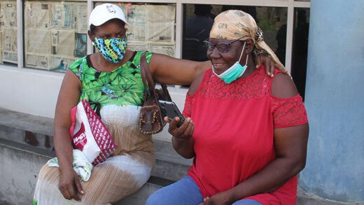 The accused, Annamay Lewis, right, is embraced by her sister, Janneemay Lewis, as she talks on the phone after security bail on Monday. (iWN photo)