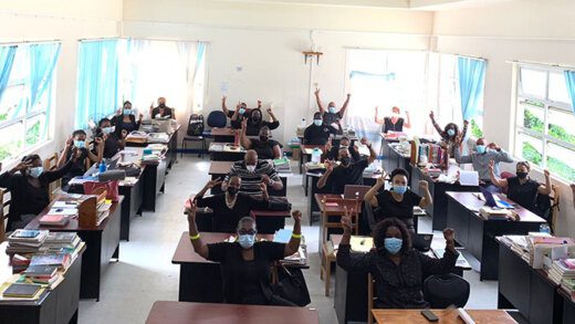 Teachers with hands raised, representing "represent peace and strength standing as one".