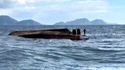 The two survivors on the overturned hull of the MV Fair Chance. (Photo: Trinidad Express)