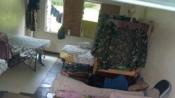 A Special Services Unit officer sleeps on mattresses on the floor in room with missing floor files and louvers at the SSU base in Old Montrose. 
