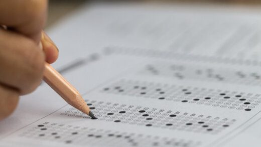 Education school test concept : Hands student holding pencil for testing exams writing answer sheet or exercise for taking fill in admission exam multiple carbon paper computer at university classroom