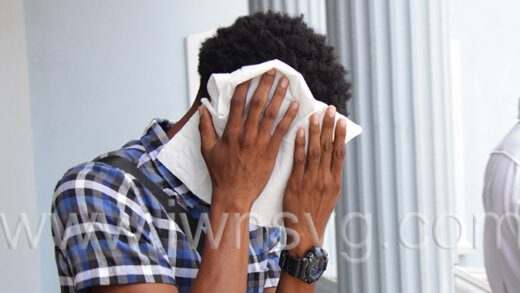 The defendant, Zackerie Latham hides his face as he leaves the Calliaqua Magistrate's Court on Tuesday, Aug. 30, 2022.
