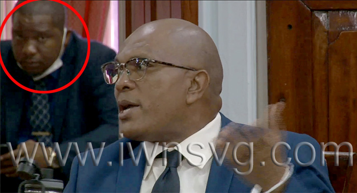 Opposition lawmaker Nigel "Nature" Stephenson responds to House Speaker Rochelle Forde's instruction to wear a mask or leave the assembly chamber on Monday, Oct. 17, 2022. An unmasked member of the Prime Minister's Security Detail is seen behind Stephenson. 