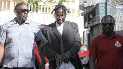 Detectives Sergeant Biorn Duncan, left, and acting Corporal Edmund Ollivierre, right escort accused murderer Abdul Garrick to the Serious Offences Court on Monday, Feb. 20, 2023. 