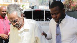 Detective Constable Strongson Soleyn, right, assist the defendant, John Felix Bristol as he walks outside the Serious Offences Court on Monday, Feb. 27, 2023.