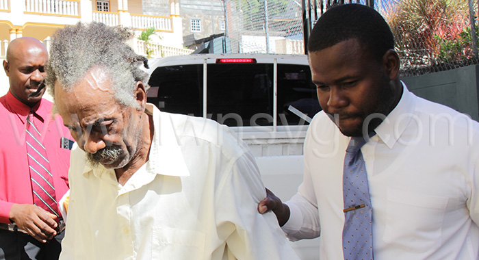 Detective Constable Strongson Soleyn, right, assist the defendant, John Felix Bristol as he walks outside the Serious Offences Court on Monday, Feb. 27, 2023.