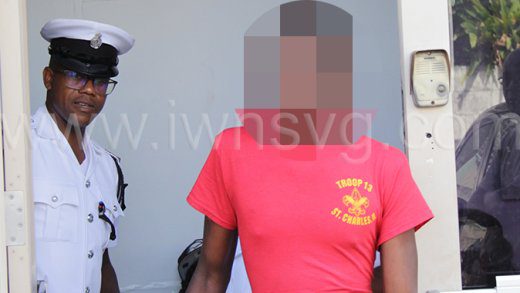 Police officer keeps a tight hand on the teen burglar as he leaves the Kingstown Magistrate's Court on Thursday, Feb. 23, 2023