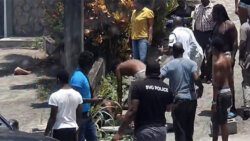Police and civilians at the scene in Rillan Hill on Thursday, April 13, 2023, where police shot and injured Dwayne Moses, a mentally ill villager. 