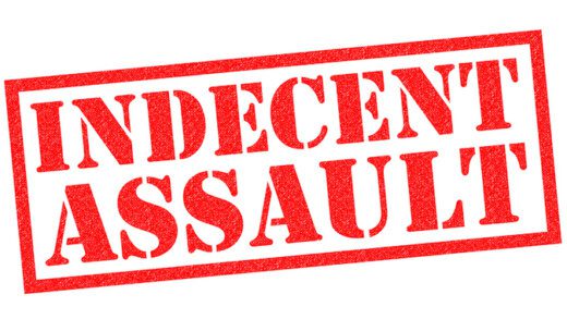 INDECENT ASSAULT red Rubber Stamp over a white background.