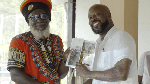H2E farmer Percy Jocelyn is presented with a booklet, aerial photo and farm supplies by Minister James.