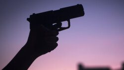 Hand of young woman holding pistol revolver gun