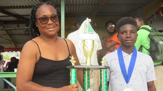 Mayreau Junior Sailors' president Helen Forde presenting the Most Outstanding Sailor trophy to 14-year old Jerimiah Forde,