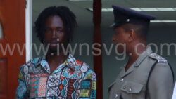 The defendant Esron Cuffy, left, interacts with a police officer outside the Colonarie Magistrate's Court, sitting at Georgetown on Thursday, May 23, 2024.