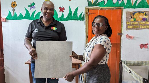 Herline Alexander, head supervisor of Marriaqua Methodist Preschool, right, receives the donation from Carlos James of CMT.