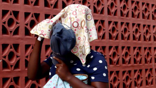 Shontel Jackson hides her face on Thursday, May 23, 2024 as she leaves the Colonarie Magistrates Court sitting at Georgetown. 
