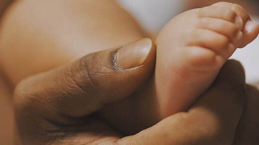 Black father playing with baby feet. Close up. High quality photo