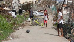 Children in Mayreau play football on a street on Tuesday July 9, 2024, near debris left by the passage of Hurricane Beryl on July 1, 2024. 
