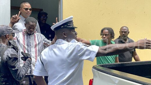 Police escort murder accused Orande Dunbar aka Bells, second from left and  Michael Olan Lyscott, second from right, from the Serious Offences Court on Friday, July 19, 2024.