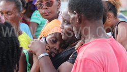 Shemille Peters, the mother of the two children who died in the fire, is consoled as she speaks on a cellular phone outside the police cordon in Georgetown on Wednesday, Oct. 23, 2024. 