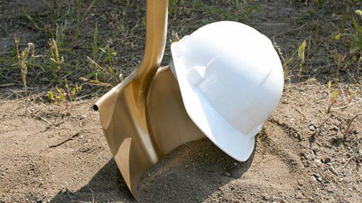 A hard hat and golden shovel await  their use in a groundbreaking ceremony.