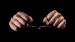 Human hands in handcuffs and torn chains