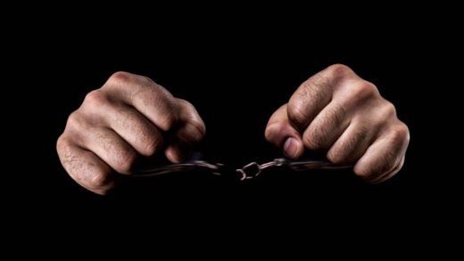 Human hands in handcuffs and torn chains
