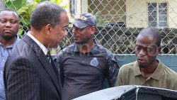 Defence counsel Michael Wyllie, second from left, in conversation with his client, Ozari Jelani Dennie, right, as the arresting officer, detective Sergeant Glendon David, left and anther police officer look on outside the Serious Offences Court in Kingstown on Tuesday, Sept. 23, 2025. 
