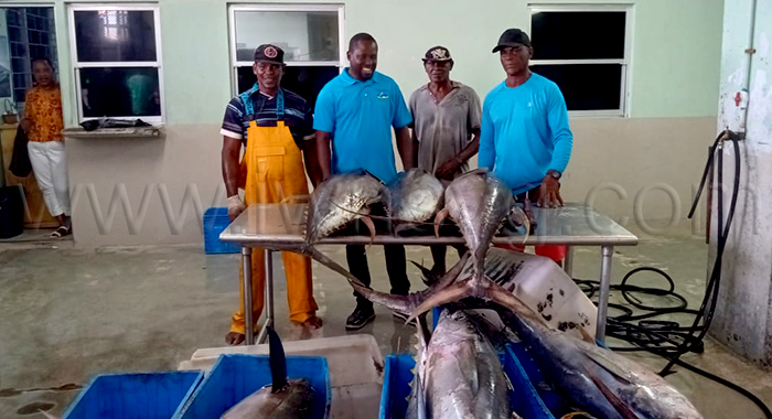 Eli Slater, right, along with Fisheries Minister Conroy Huggin, second left, at the Kingstown Fish Market where Slater landed his winning catch on Monday, May 25, 2026. 