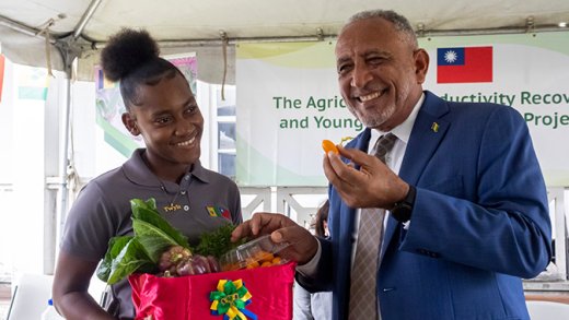 Prime Minister Godwin Friday, right, and a participant in the Agricultural Productivity Recovery and Young Farmers Training Project at the launch in Orange Hill on Tuesday, May 19, 2026.