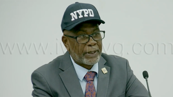 Deputy Prime Minister and National Security Minister St. Clair Leacock wears an "NYPD" cap as he speaks in Parliament on Aug. 27, 2026.